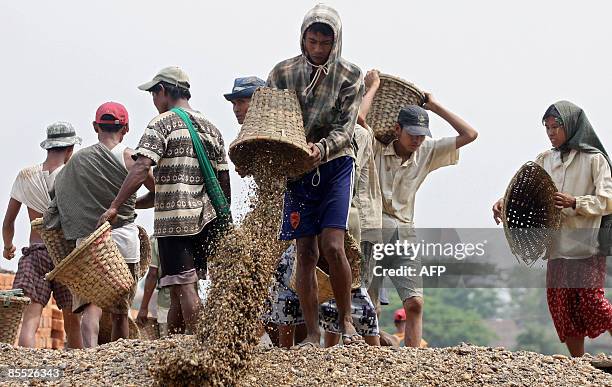 Workers carry basket of gravels at Mingalar Taung Nyunt Township in Yangon on March 18, 2009. Myanmar authorities have arrested five members of...