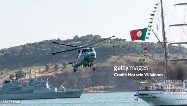 Lynx helicopter flies by Portuguese Navy tall ship and school ship NRP Sagres laying at anchor in Tagus River during the commemoration of the 100th...