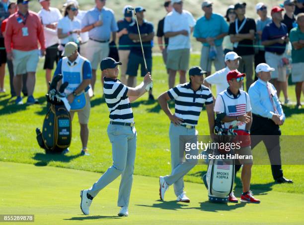 Daniel Berger of the U.S. Team plays a shot as teammate Brooks Koepka looks on during the Thursday foursomes matches of the first round of the...