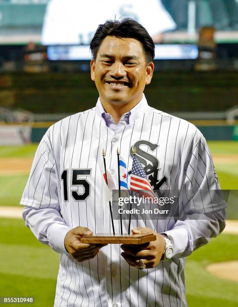 Former Chicago White Sox player Tadahito Iguchi holds miniture flags and smiles while he is honored by Naoki Ito ·, consul general of Japan in...