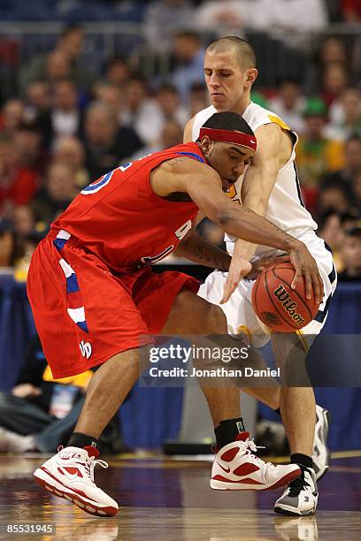 Charles Little of the Dayton Flyers drives the ball in the first half against Alex Ruoff of the West Virginia Moutaineers during the first round of...