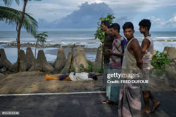 People stand next to the covered body of Rohingya Muslim refugee near Inani beach, Cox's Bazar on September 29, 2017. At least 15 people drowned and...