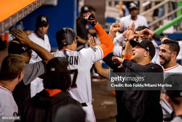 Giancarlo Stanton of the Miami Marlins celebrates with Martin Prado in the dugout after hitting his fifty-ninth home run of the season as Mike Aviles...