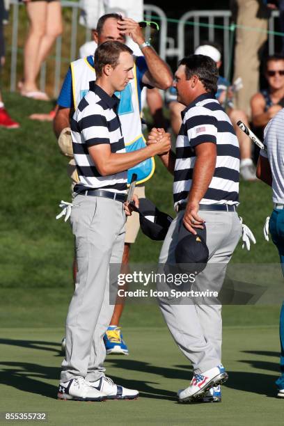 Golfers Jordan Spieth and Patrick Reed shake hands after winning their match on the 14th hole during the first round of the Presidents Cup on...