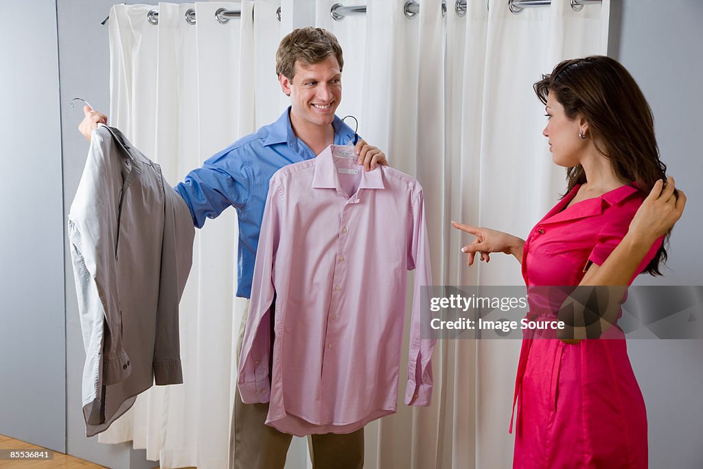 A woman helping a man choose a shirt