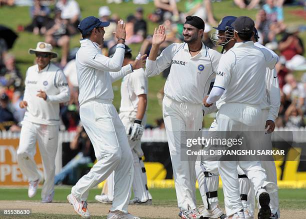 India's V.V.S. Laxman joins teammates to congratulate bowler Harbhajan Singh for taking the wicket of New Zealand batsman Jesse Ryder during the...