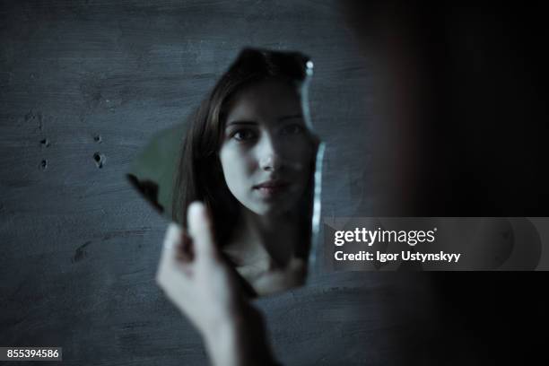 portrait of depressed woman with mirror indoors on the dark background - alleen één jonge vrouw stockfoto's en -beelden