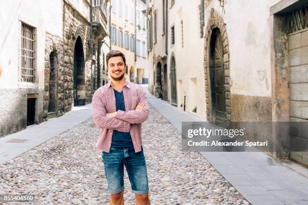 young smiling man on the street of the old town in bergamo, lombardy, italy - italienischer abstammung stock-fotos und bilder