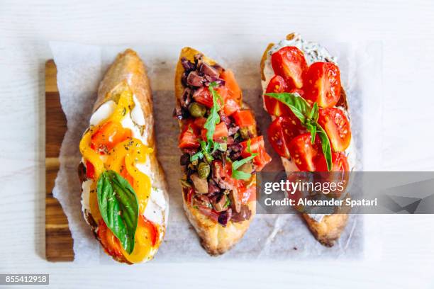 directly above close up shot of bruschettas with tomato, basil, capers, bell pepper and cheese - bruschetta stock pictures, royalty-free photos & images