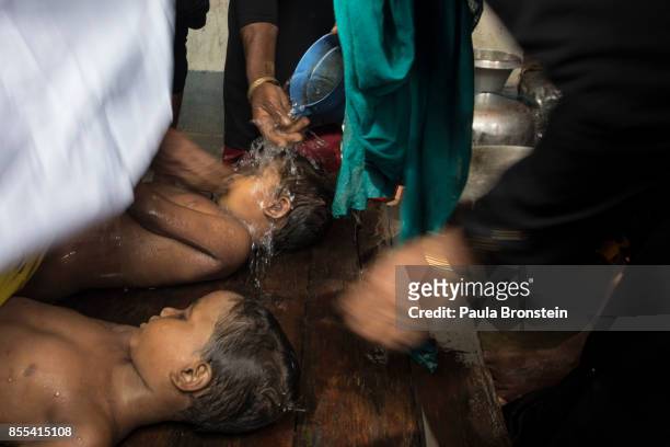 The bodies of children are washed by women in preparation for the funeral after a boat sunk in rough seas off the coast of Bangladesh carrying over...