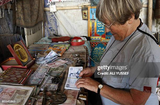 British national Bridget Jones inspects old Iraqi money bills dating back to Saddam Hussein's era as she shops for souvenirs in Baghdad on March 21,...