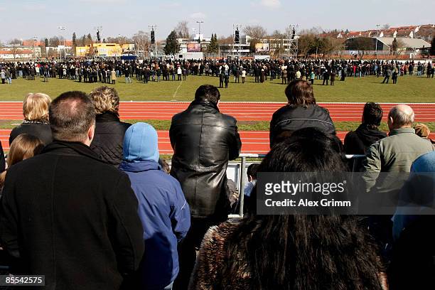 Mourners follow a church service on video screens at a sports field near Albertville high school on March 21, 2009 in Winnenden near Stuttgart,...
