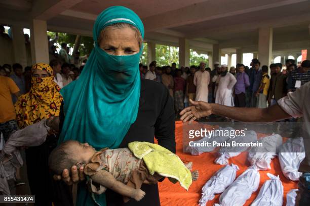 Woman carries the body of a child to be washed in preparation for the funeral after a boat sunk in rough seas off the coast of Bangladesh carrying...