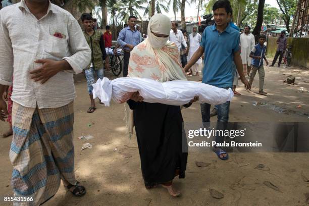 Woman carries the body of a child in preparation for the funeral after a boat sunk in rough seas off the coast of Bangladesh carrying over 100 people...