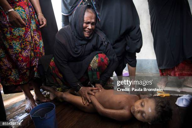 Woman weeps while bathing the bodies of children in preparation for the funeral after a boat sunk in rough seas off the coast of Bangladesh carrying...