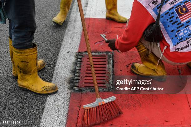 Workers repair a drain cover after Haas F1's French driver Romain Grosjean suffered a frightening tyre explosion during the second practice session...
