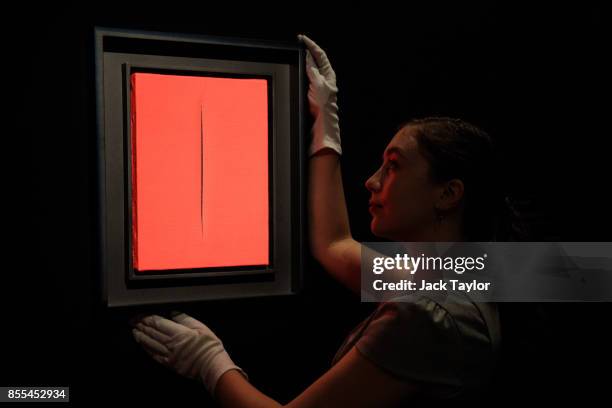 An employee poses with 'Concetto spaziale, Attesa' by Lucio Fontana at Christie's London on September 29, 2017 in London, England. Christie's Auction...