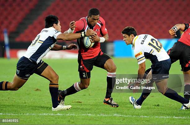 Christian Lealiifano and Tyrone Smith of the Brumbies tackle Ashwin Willemse of the Lions during the Super 14 match between Auto & General Lions and...