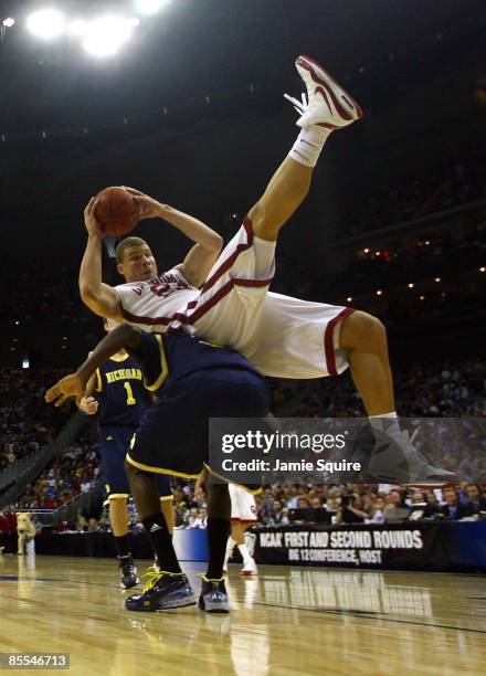 Blake Griffin of the Oklahoma Sooners falls on the back of Manny Harris of the Michigan Wolverines during the second round of the NCAA Division I...