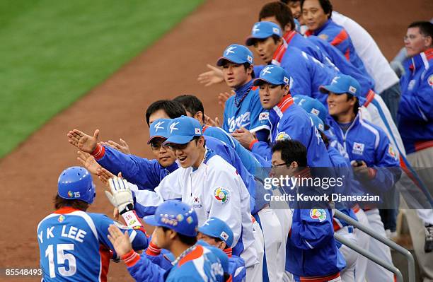 Yong-Kyu Lee of Korea celebrates with teammates after scoring on a single by teammate Hyun-Soo Kim the during the first inning of the semifinal game...