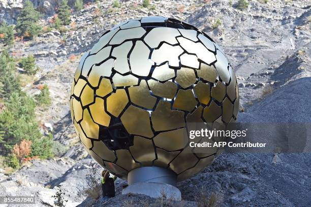 Man stands next to the memorial "Sonnenkugel", a sculpture by German artist Jurgen Batscheider, on September 29, 2017 in the French Alps above the...