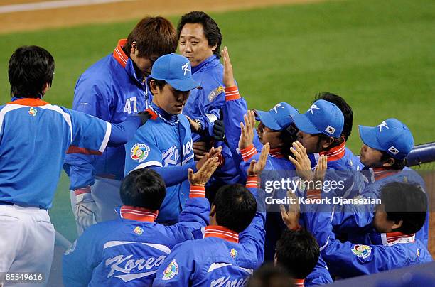 Starting pitcher Suk-Min Yoon of Korea is congratulated by teammates after being taken out in the seventh inning during the semifinal game of the...