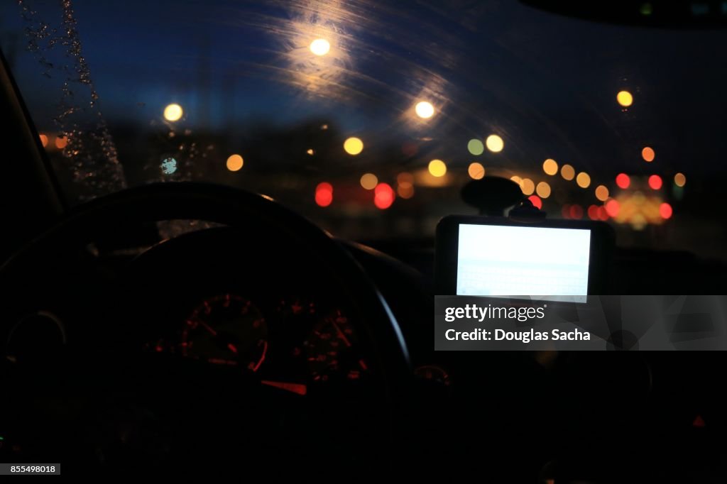 Dashboard view of a moving car on a rainy night
