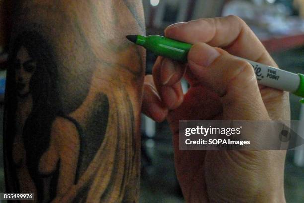 Gary Jones is seen drawing a design on a client hand before the permanent tattoo. Gary Jones is one of the Kadazan talented tattoo artist from...