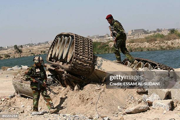 Iraqi soldiers inspect the wreckage of an old Iraqi tank destroyed during the 2003 US-led invasion in the southern city of Basra on March 22, 2009....