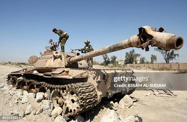 Iraqi soldiers inspect the wreckage of an old Iraqi tank destroyed during the 2003 US-led invasion in the southern city of Basra on March 22, 2009....