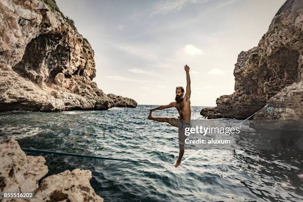 man practicing slacklining over the sea - rope walking stock pictures, royalty-free photos & images