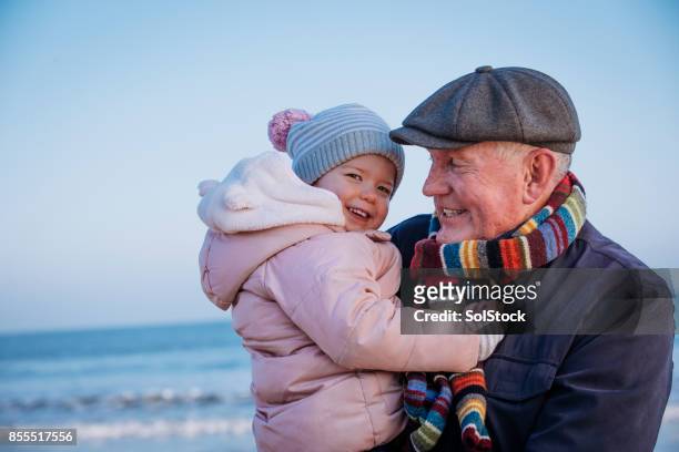 grandfather with his granddaughter on the coast - multi generation family winter stock pictures, royalty-free photos & images