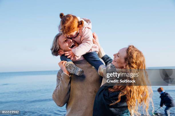 family enjoying being out at the beach - shoulder rides stock pictures, royalty-free photos & images