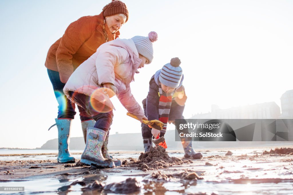 Grandmother with her Grandchildren Digging in the Sand