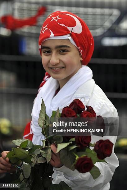 Twelve-year old Buersa from the muslim community distributes roses to visitors in front of the new Kocatepe Mosque during its inauguration on March...
