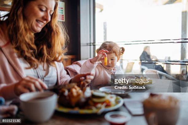 mother and daughter enjoying food at a beach cafe - fish and chips stock pictures, royalty-free photos & images