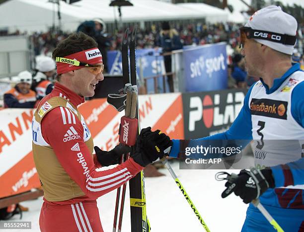 France Vincent Vittoz congratulates Switzerland's Dario Cologna to the victory in the men's 15 km pursuit during the Cross Country skiing world cup...