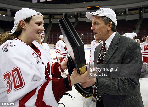 Jessie Vetter of the Wisconsin Badgers hands off the championship trophy to head coach Mark Johnson after they defeated the Mercyhurst Lakers on...