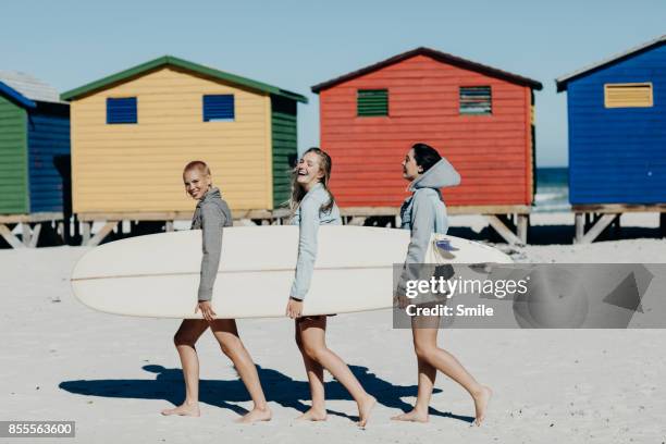 three girls walking with a long board - african travel smile foto e immagini stock