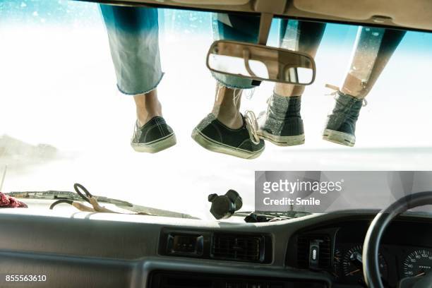legs tangling on a car’s windscreen - lustige füße stock-fotos und bilder