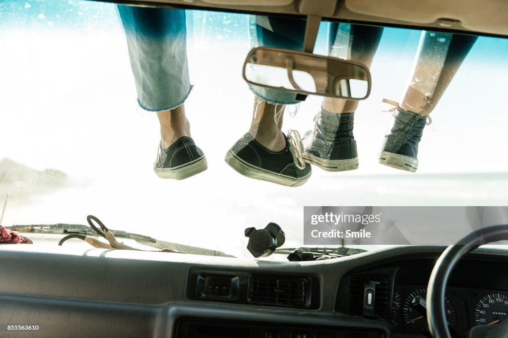 Legs tangling on a car’s windscreen