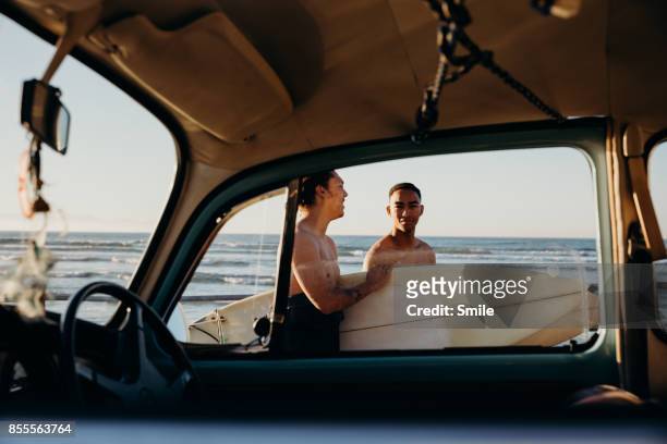 Two surfers seen through car window