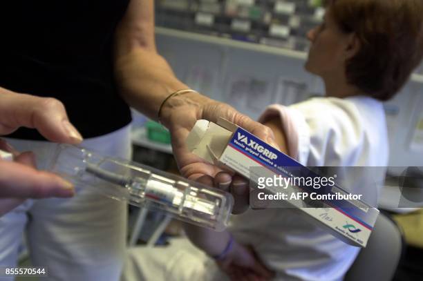 Une infirmière présente le contenu d'une boîte de vaccin grippal alors qu'une patiente attend de se faire vacciner, le 14 novembre 2003 à Caen. A ce...