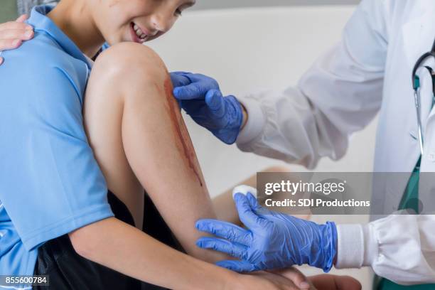 emergency room doctor cleans young boy's wounded knee - bloody leg stock pictures, royalty-free photos & images