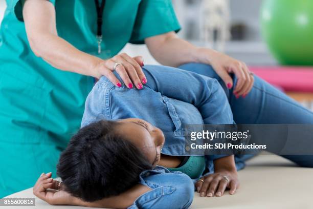 unrecognizable chiropractor adjusts a mid adult woman - hip stock pictures, royalty-free photos & images