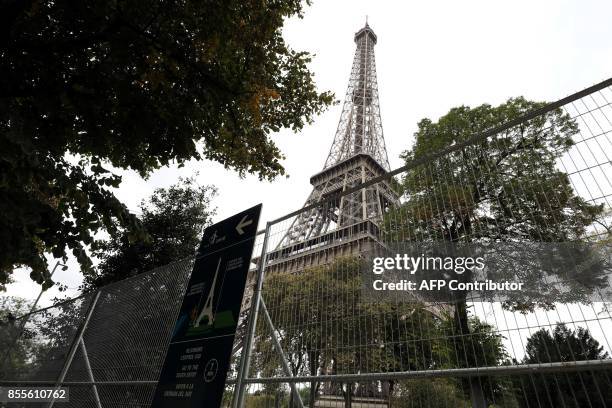 Picture taken on September 29, 2017 shows metal gates set up for the construction of bulletproof glass walls set to go up around the Eiffel Tower, in...