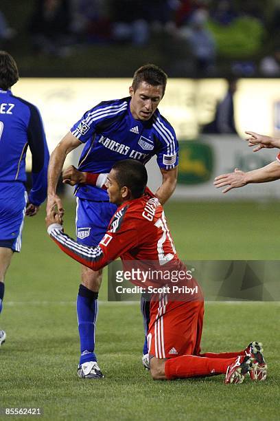 Davy Arnaud of the Kansas City Wizards helps Amado Guevara of Toronto FC get up during the game at Community America Ballpark on March 21, 2009 in...