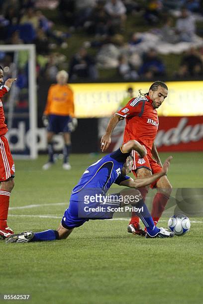 Davy Arnaud of the Kansas City Wizards tackles Dwayne De Rosario of Toronto FC during the game at Community America Ballpark on March 21, 2009 in...