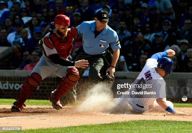 Ian Happ of the Chicago Cubs is safe at home plate as Tucker Barnhart of the Cincinnati Reds can't handle the throw during the second inning on...