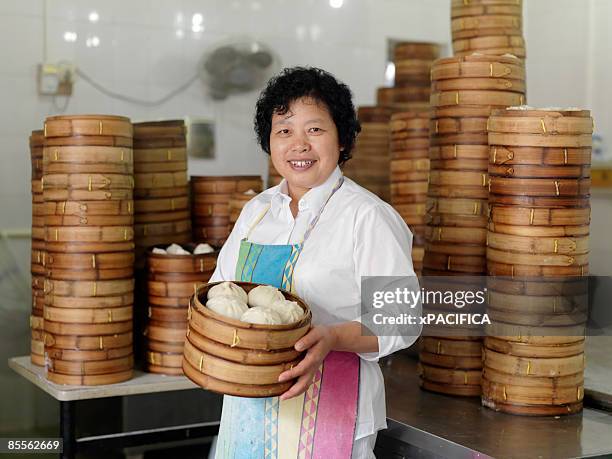 a portrait of a woman holding dim sum buns.  - panchina stockfoto's en -beelden